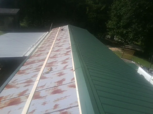 Old rusted panels beside newly installed green metal roofing — Wind Damage Roof Repair by Roofing Brothers in Casselberry
