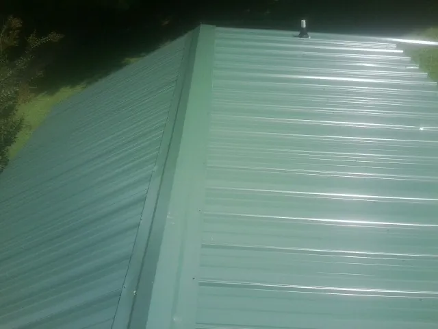 New green metal panels meeting at the ridge of a roof — Flat Roof Repair work by our crew in Casselberry