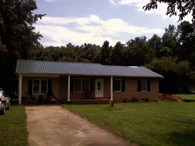 Dark green metal roof on a brick ranch with a covered porch in Casselberry